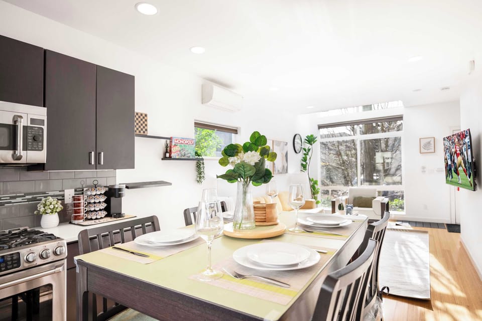 Dine in style! This beautifully set dining space offers an intimate atmosphere with elegant tableware, lush greenery, and an open layout for a memorable mealtime experience.