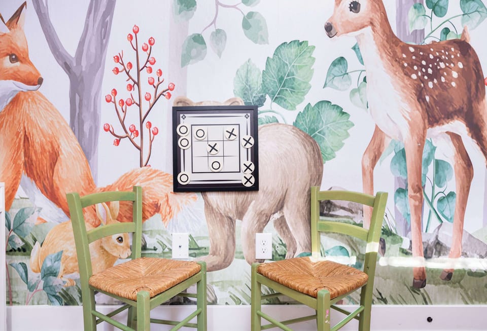  Another angle of the purple bedroom, showing the bunk bed, framed animal artwork, and green chairs.