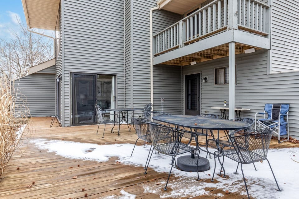 Rear deck furnished with an outdoor dining table and chairs beside the attached building.