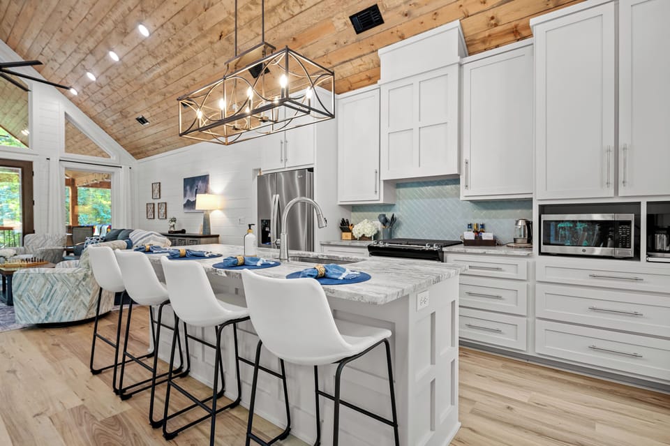 Gather in a modern rustic kitchen with white cabinets and island seating.
