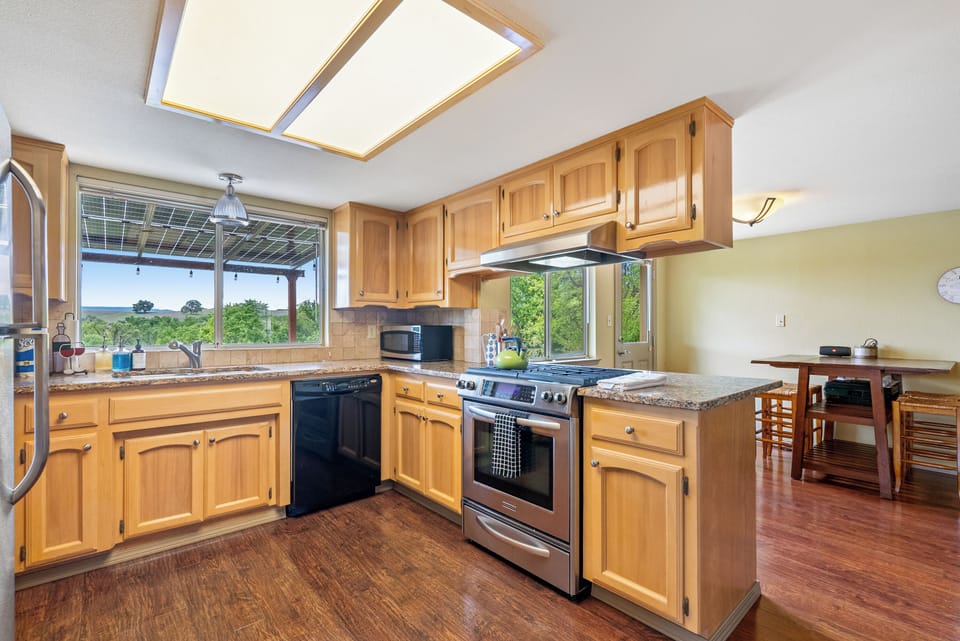 This bright and functional kitchen features warm wood cabinetry, elegant granite countertops, and a full suite of stainless steel modern appliances.