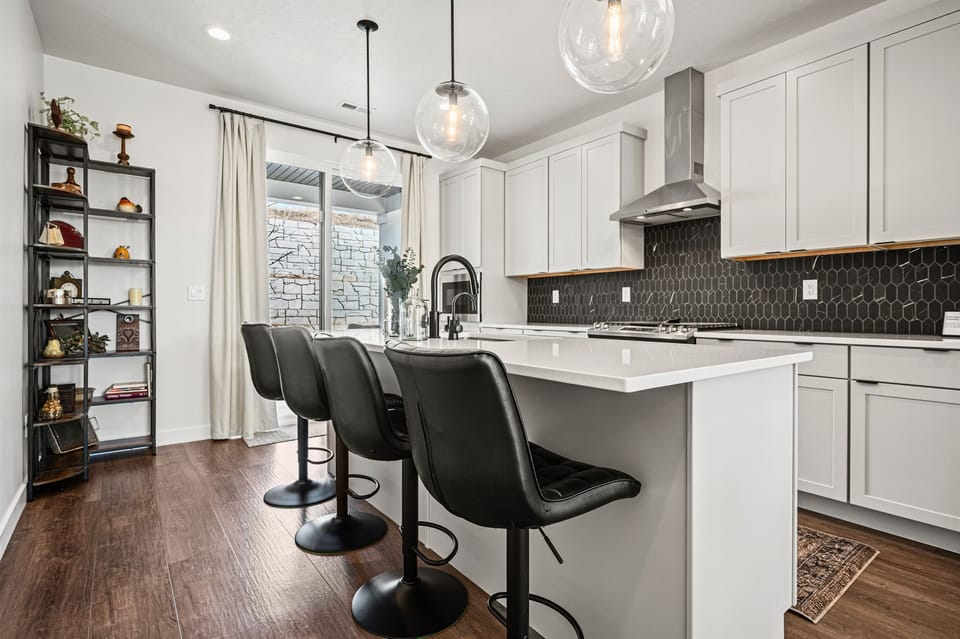 The gourmet kitchen features an island with seating for four and is equipped with brand-new stainless steel appliances, including a microwave and gas stove.