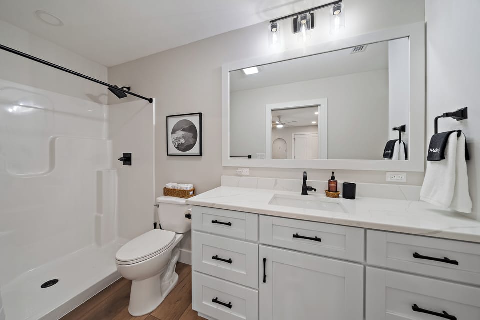 Full bath with standing shower, and a sink vanity located through bedroom 2.