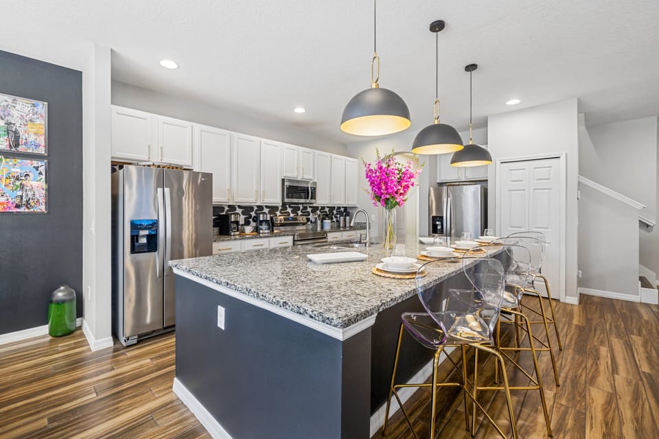 - Modern kitchen with granite countertops and island  
- Bar seating with transparent chairs and pendant lights  
- Fully equipped with stainless steel appliances set