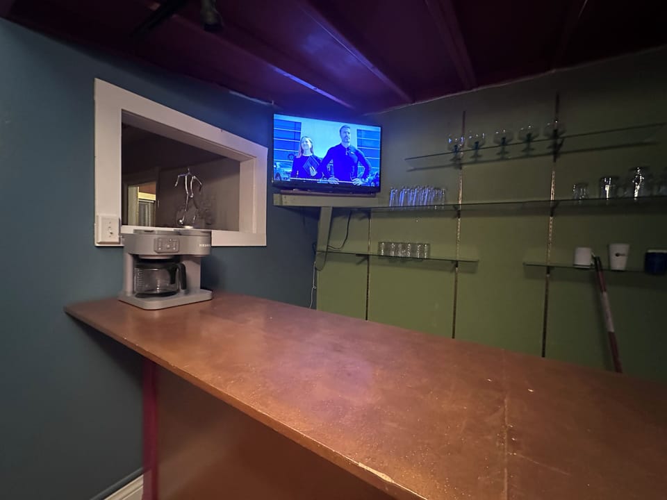 Coffee bar with 3 stools and a tv.