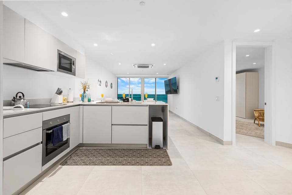 Your modern, fully-equipped kitchen opens to stunning turquoise ocean views. Bright, sleek, and ready for preparing fresh coastal meals, it's the heart of your beachside escape.