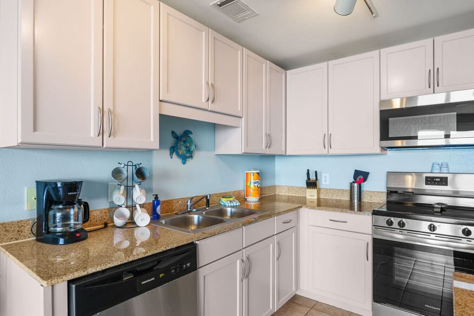 Modern kitchen with granite countertops, ample storage, and a sleek stainless steel refrigerator