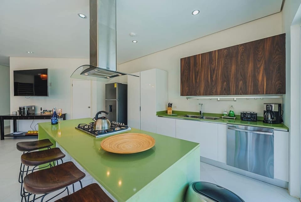 A fully equipped and spacious kitchen designed to brighten your day—featuring a fresh blend of lime green, warm wood, and crisp white tones. With a perfect view of the pool area, cooking here feels like a true island experience.