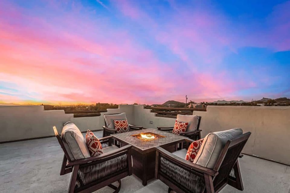 Cozy rooftop seating with a fire pit and stunning sunset views.