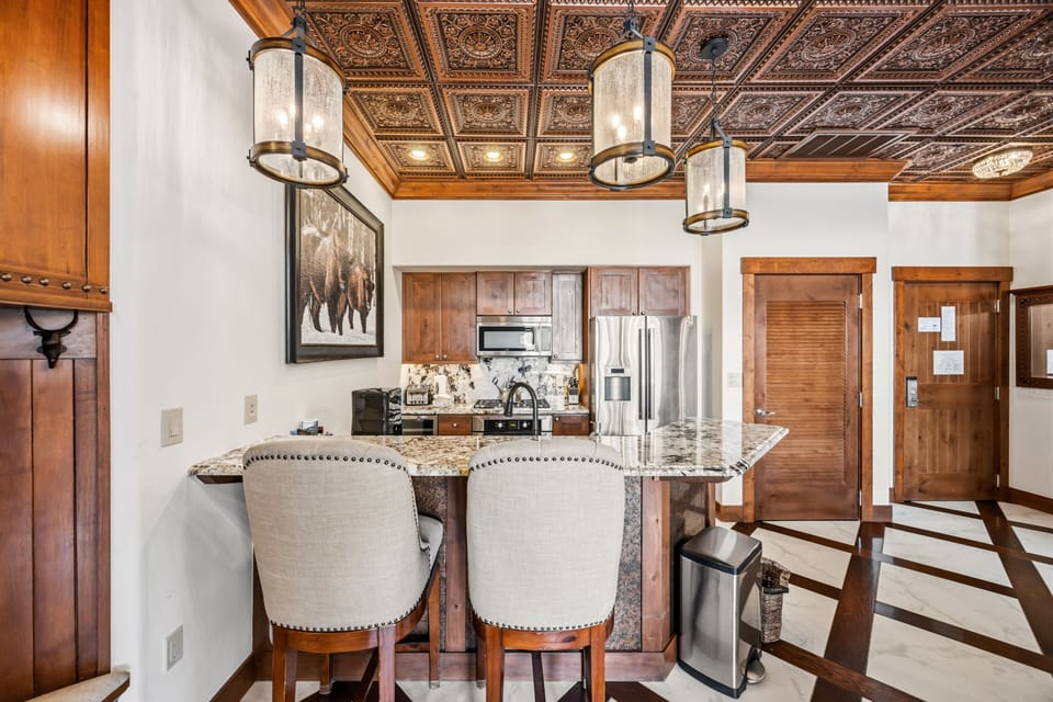 Breakfast bar — tufted seating beneath copper pendants.