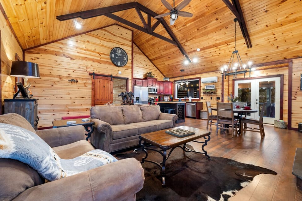An inviting living area with leather seating, vaulted ceilings, and an open design connecting the kitchen, dining, and living spaces.