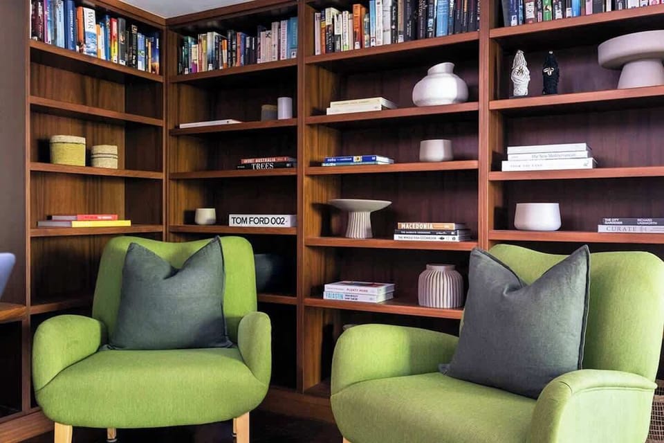 Lose yourself in a good book in the inviting library, featuring vibrant seating, wooden shelves, and a carefully curated collection for a peaceful hideaway.