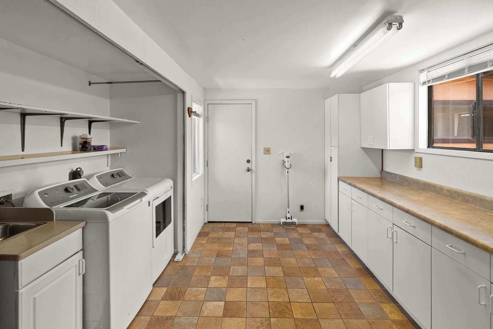 Spacious laundry room with washer, dryer & extra storage.