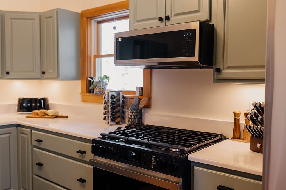 The kitchen features a gas range, large stainless French-door refrigerator, microwave, spice rack, Zwilling knife block, and a sleek SMEG toaster for perfect mornings.