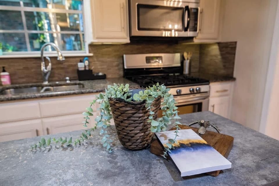 Prepare delicious home-cooked meals in this fully equipped kitchen, featuring stainless steel appliances including a gas range and built-in microwave, durable granite countertops, and off-white cabinetry.