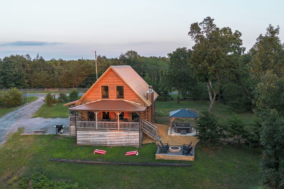 Bird's eye view of cabin, fire pit, hot tub, corn hole and grill areas