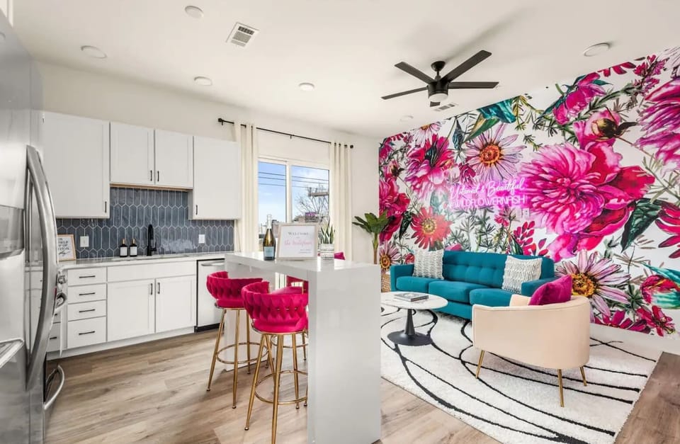 Living Room: Enjoy a beautifully designed space with a vibrant floral accent wall, stylish bar seating, and a cozy lounge area.