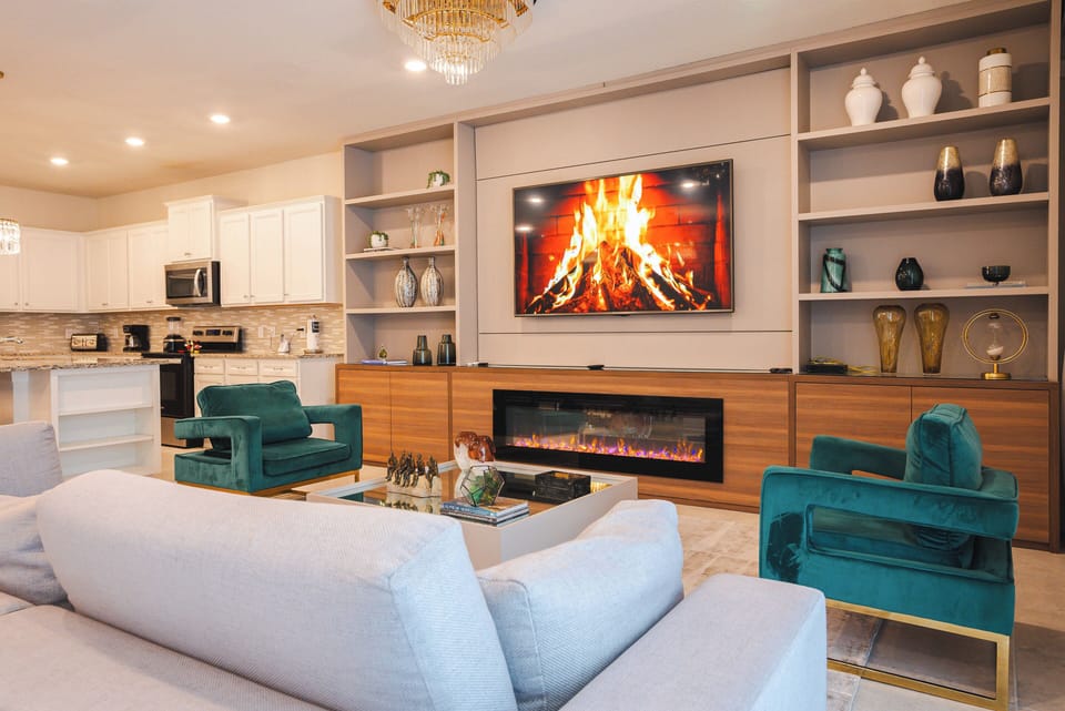 Experience a stylish living area with plush, light-colored sofas and vibrant teal chairs, perfect for relaxation. Enjoy the cozy fireplace and modern media wall, making it an ideal spot to unwind after your day of adventures.