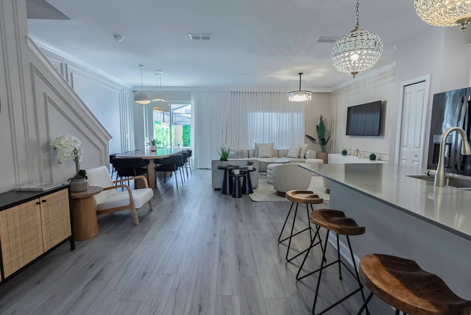 Experience a bright, airy living space featuring elegant light wood floors and modern furnishings. The spacious kitchen island with stylish bar stools is ideal for gatherings, and large windows bring in natural light and stunning.