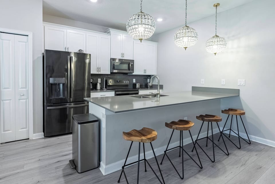Enjoy a beautifully designed kitchen with sleek white cabinetry and a spacious island ideal for casual dining. Warm wood accents and elegant pendant lighting create a welcoming atmosphere for your culinary adventures.