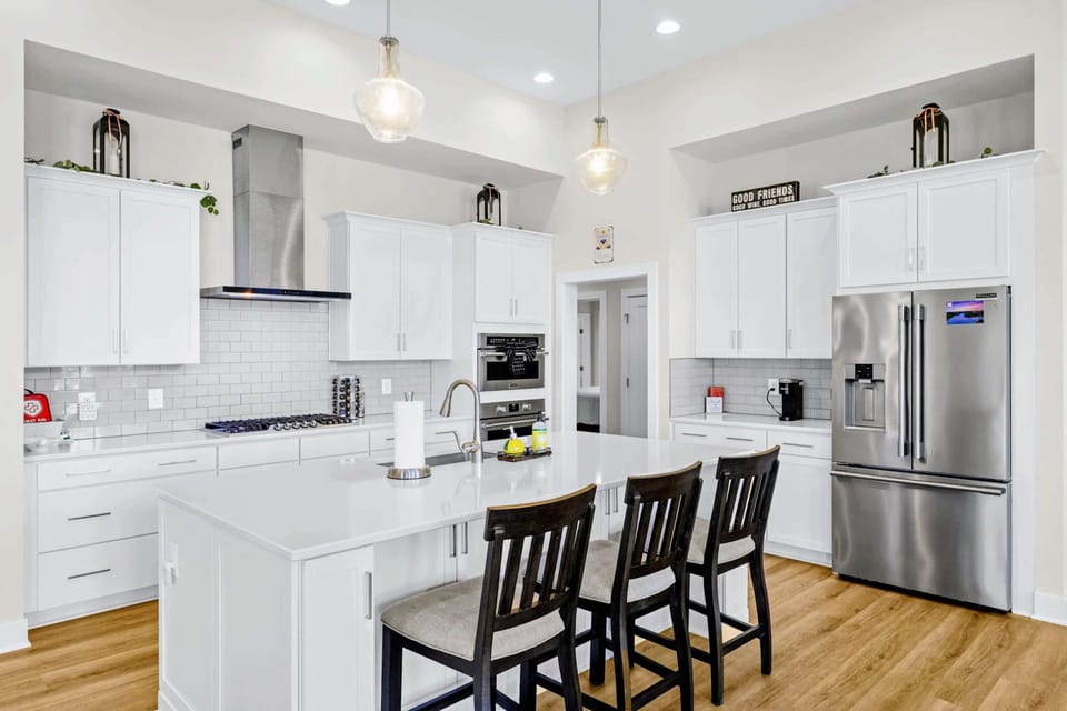 Kitchen - Symmetrical view of the island bar with three stools, gas cooktop, double ovens, and the big French-door fridge.