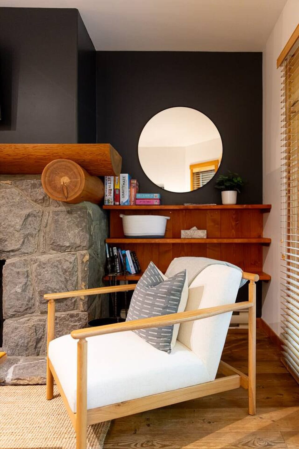 A cozy living space featuring a modern white armchair with a wooden frame and a patterned gray pillow. Perfect for relaxing and reading books.