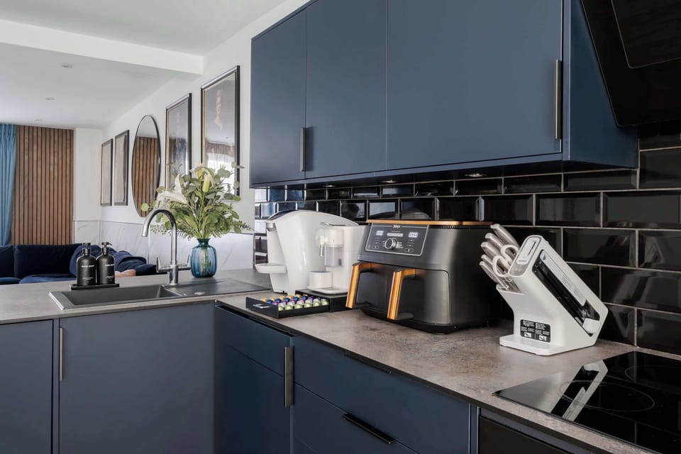 Full Kitchen | A kitchen fully equipped with everything needed for a comfortable stay, including a water dispenser, modern appliances, full cookware, and a dining table. The space flows directly into the private garden for a smooth and social layout.