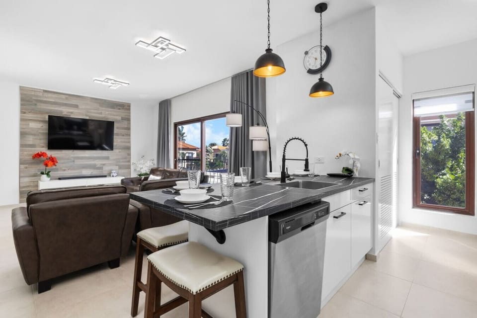 Enjoy open-concept living in this stylish space, where a sleek kitchen with modern appliances flows into a cozy living area. The kitchen island offers extra seating, while large windows invite natural light into the space.