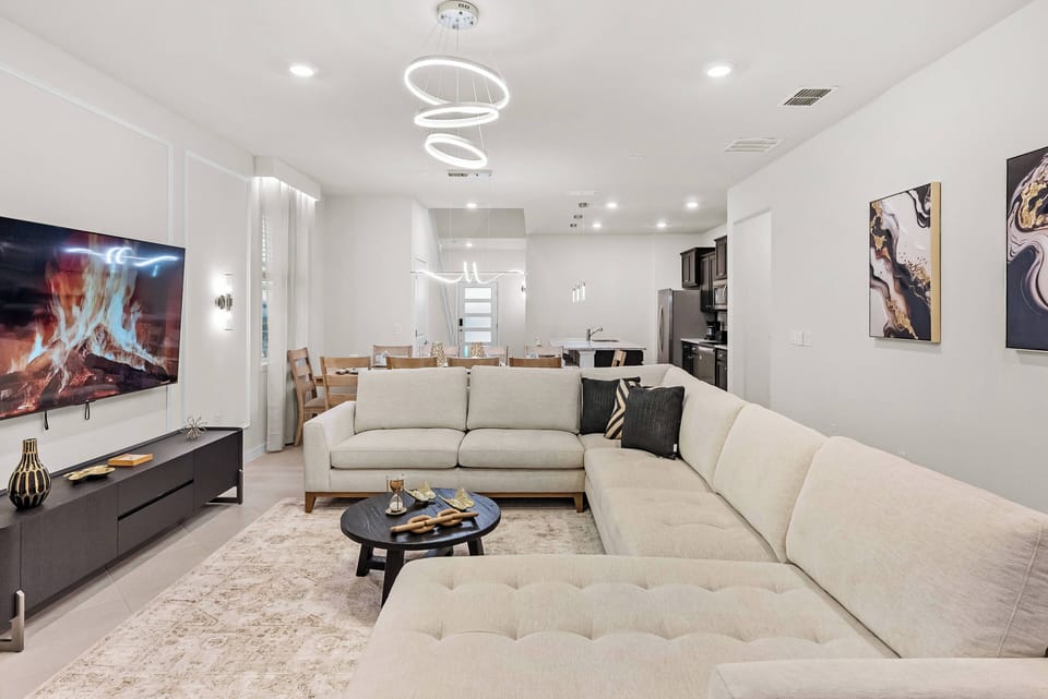 Enjoy comfort in this spacious living area with a plush sectional sofa and modern decor. Unique lighting enhances the warm tones, and artwork adds personality to create an inviting atmosphere for your stay.