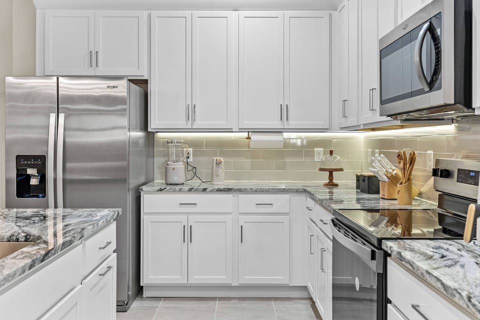 This bright and airy kitchen boasts sleek white cabinetry and beautiful granite countertops, perfect for culinary creativity. Modern stainless steel appliances and soft under-cabinet lighting make meal prep a delight.