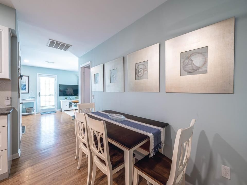 Open dining and kitchen area with coastal decor, bright lighting, and seamless flow into the living space.