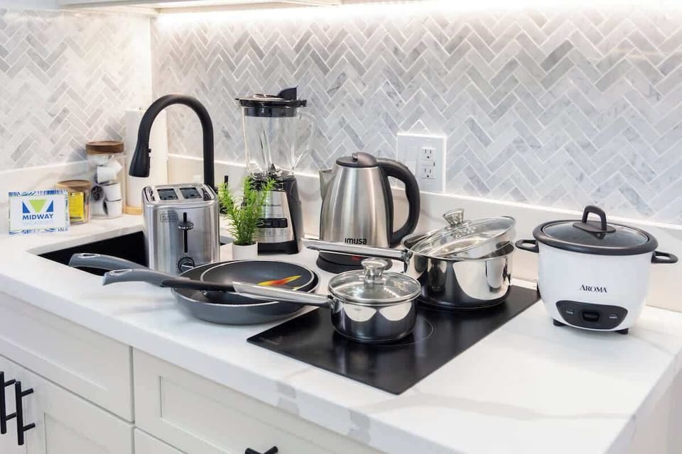 A kitchenette countertop, essential appliances, and cookware, including a toaster, blender, kettle, pots, and pans.