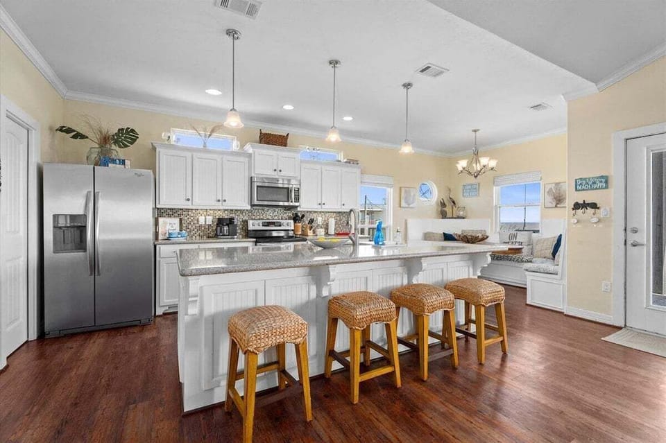 Modern coastal kitchen with oversized island seating, stainless steel appliances, and open-concept design ideal for family meals and beach vacations.