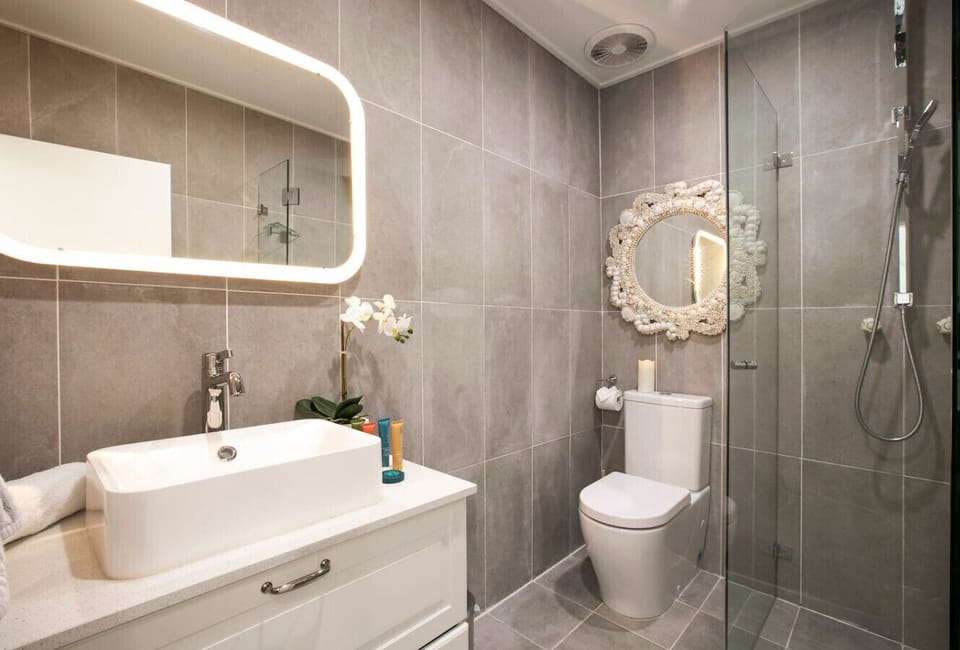 Refresh in the contemporary bathroom, complete with a walk-in rainfall shower, illuminated mirror and spacious vanity.