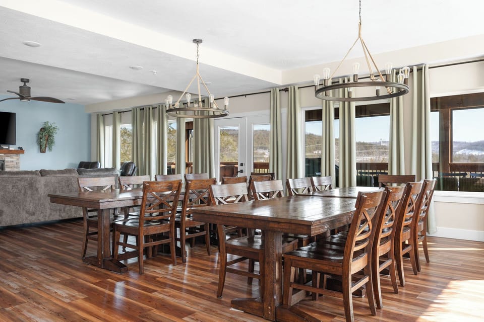 - Gather around these long wooden tables for shared meals, or morning coffee with a view through the tall windows
- Every chair invites good conversation, warm laughter, & together time
- Whether ten or more people, this space brings everyone closer