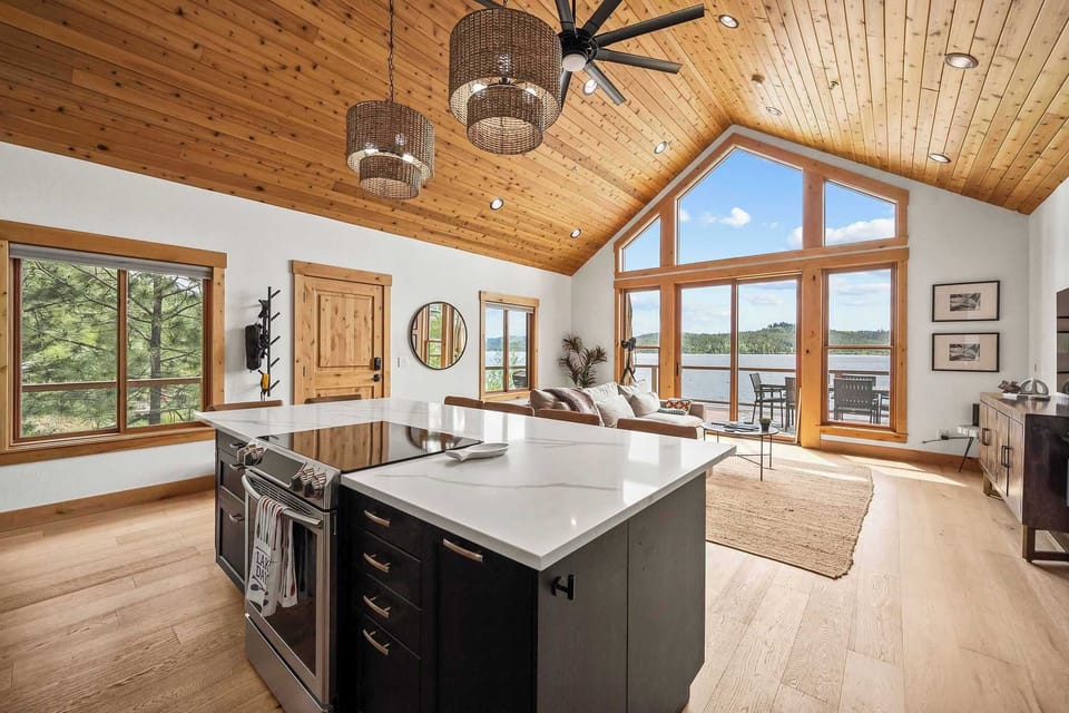 Savor lakefront living in this stunning open kitchen with soaring wood ceilings, marble island, and expansive windows framing water views.