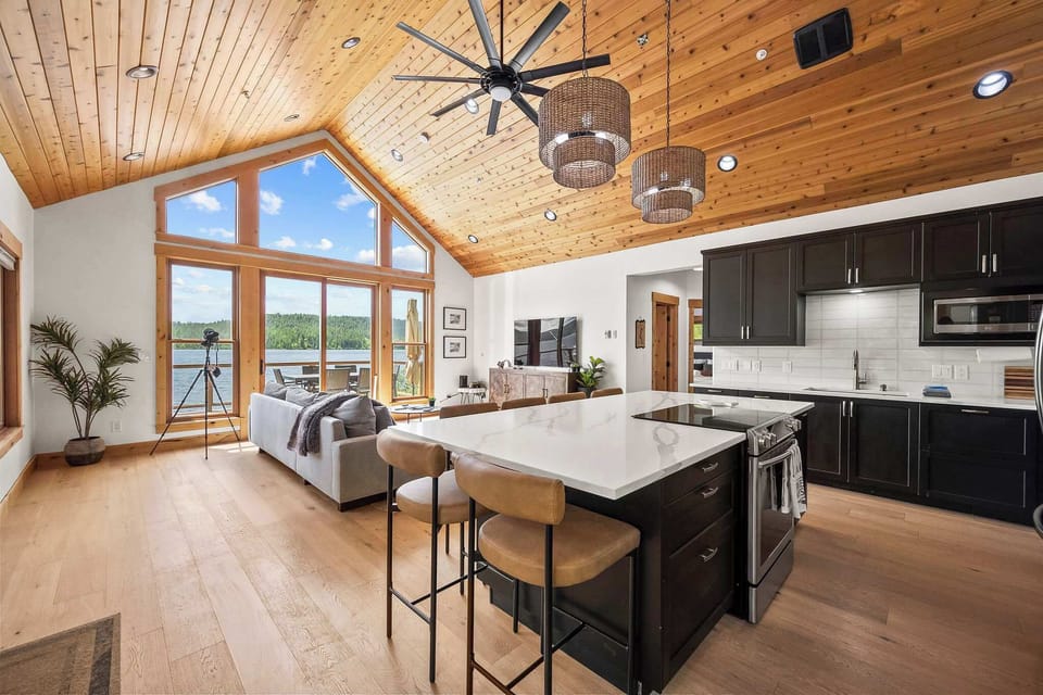 Your open-concept retreat features soaring wood ceilings, modern kitchen with island seating, and stunning lake views through floor-to-ceiling windows.