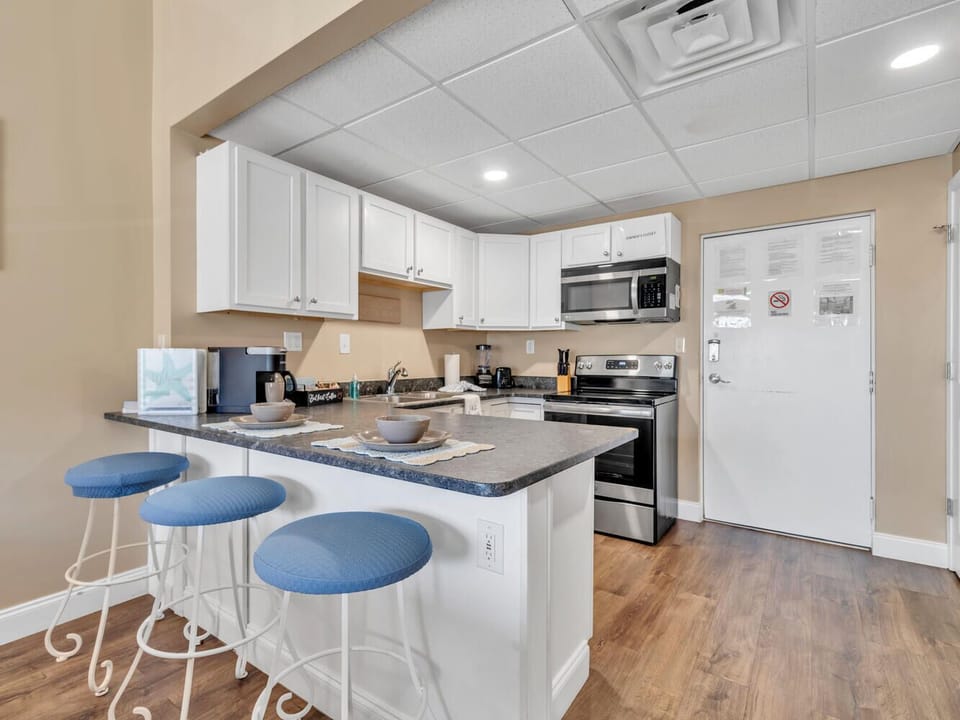 Your spacious kitchen features white cabinetry, granite countertops, and modern appliances, perfect for preparing meals and enjoying casual dining at the breakfast bar.