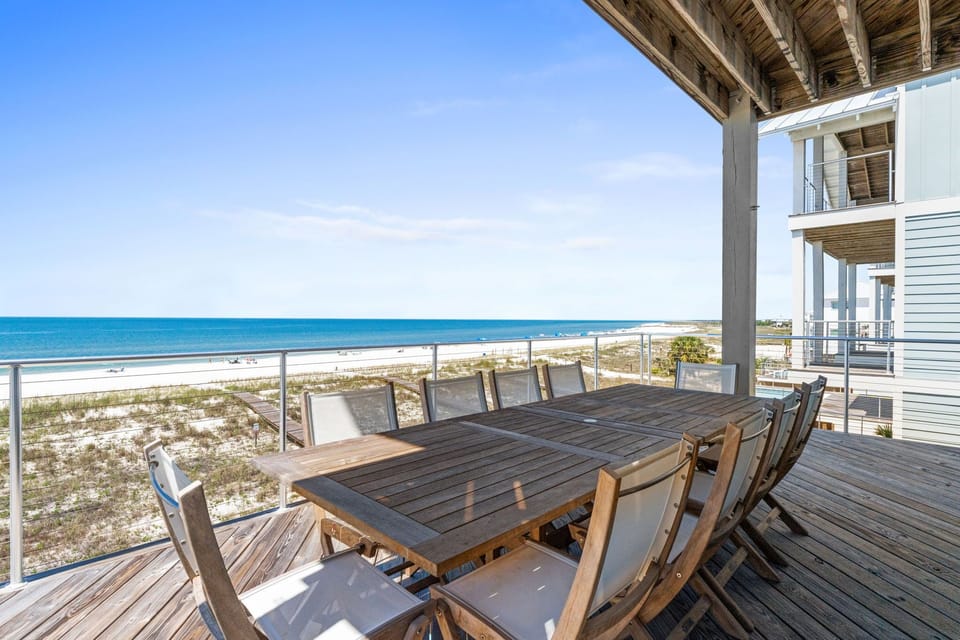 Beachfront deck with spacious dining for twelve, offering direct views of white sand beaches and turquoise waters—perfect for memorable outdoor meals.