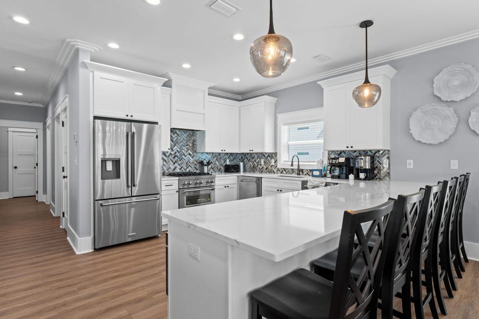 Step into your chef's dream: a spotless kitchen with gleaming counters, modern appliances, and bar seating perfect for morning coffee or evening wine with friends.