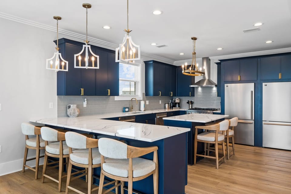 Step into this stunning chef's kitchen with elegant navy cabinetry, gleaming marble countertops, and modern stainless steel appliances. Gather around the generous island for morning coffee or evening meals in style.