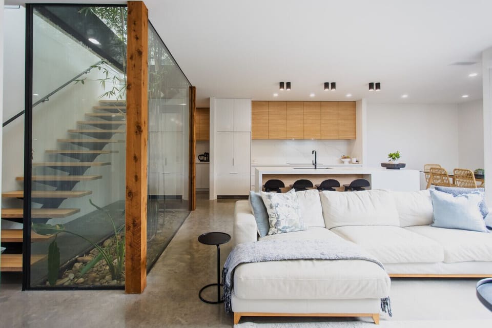 Open plan kitchen living and dining flowing onto the courtyard deck. Indoor atrium across 2 levels