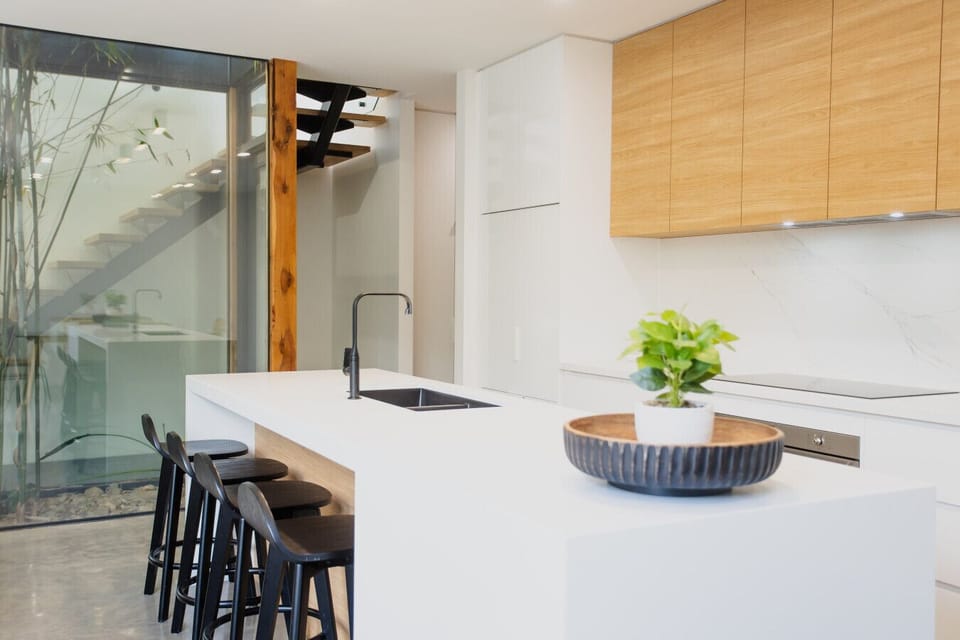 Open plan kitchen living and dining flowing onto the courtyard deck. Indoor atrium across 2 levels