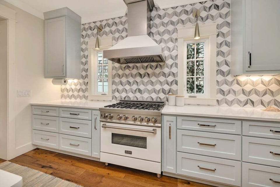 Gas range with geometric tile backsplash and white hood