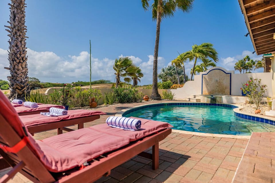 A vibrant oasis with comfy lounge chairs right by the sparkling pool, surrounded by lush tropical vibes!