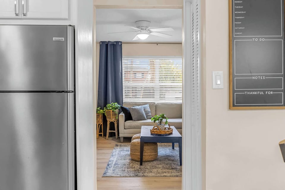 View from the kitchen into a cozy living room with natural light and modern decor.