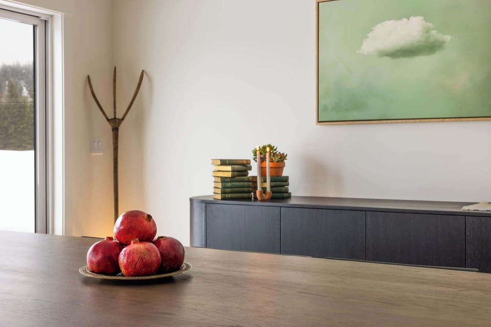This thoughtfully designed dining area blends contemporary style with warmth and charm. The rich wood tones of the table contrast beautifully with the sleek black chairs, while carefully curated décor including a dreamy cloud painting. 