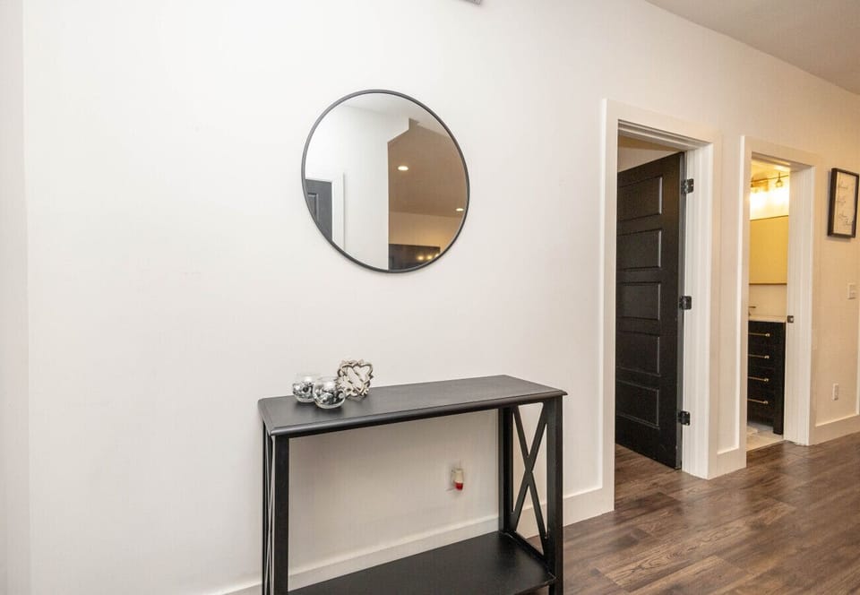 A chic nook in the hallway with a console table and circular mirror, located just outside one of the home`s modern bathrooms.
