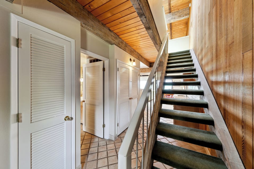Step into your charming retreat with rustic beams overhead and a striking staircase leading to your upper level sanctuary.