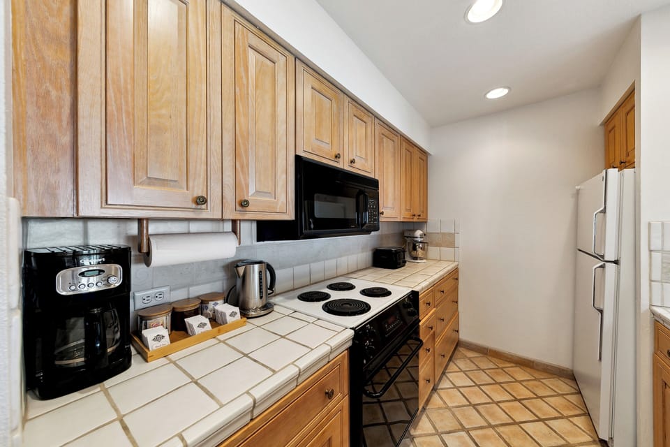 Cook your favorite meals in this fully equipped kitchen featuring warm wood cabinets, modern appliances, and tile countertops.